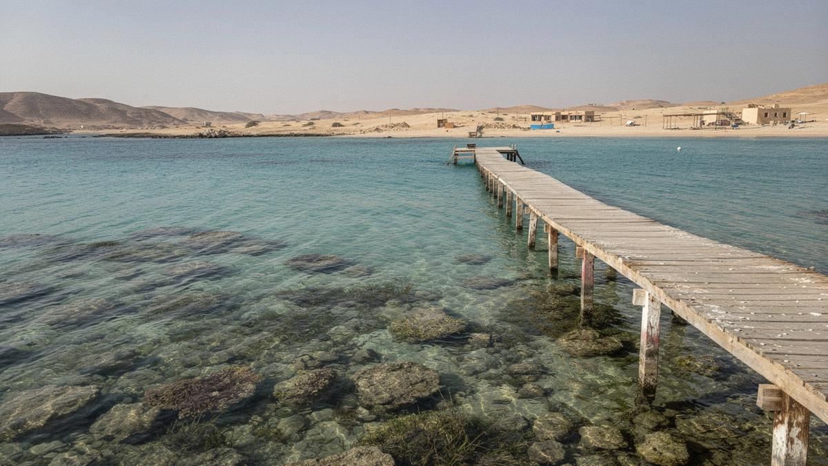 Calm Red Sea bay with coral reef and a wooden jetty beside a family hotel